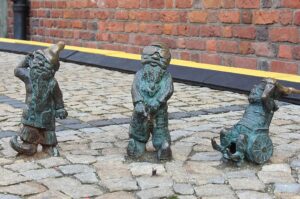 Trzy figurki wrocławskich krasnali: niesłyszący, niewidomy i siedzący na wózku.